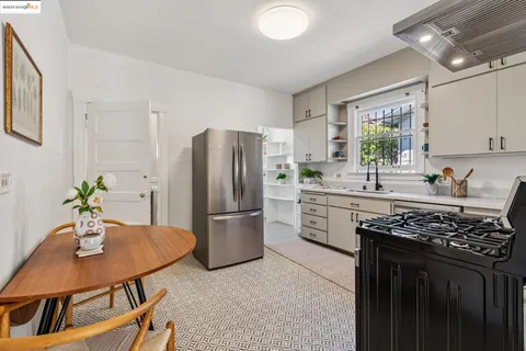 a kitchen with stainless steel appliances a stove a refrigerator a sink a table and chairs