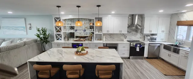 a kitchen with stainless steel appliances granite countertop a sink dishwasher and a dining table with wooden floor