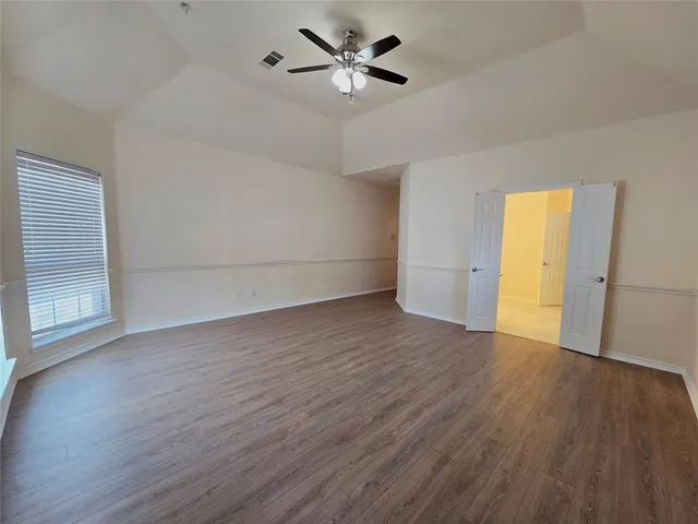 an empty room with wooden floor and a ceiling fan