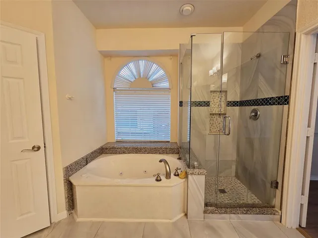a bathroom with a tub a shower and mirror