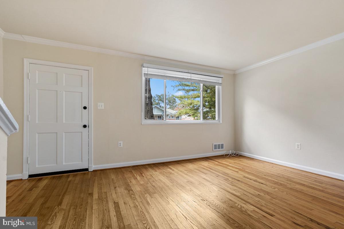 9003 Manchester Road, Unit 9003 Silver Spring, MD 20901 - Photo 6 of 53 a view of an empty room with wooden floor and a window