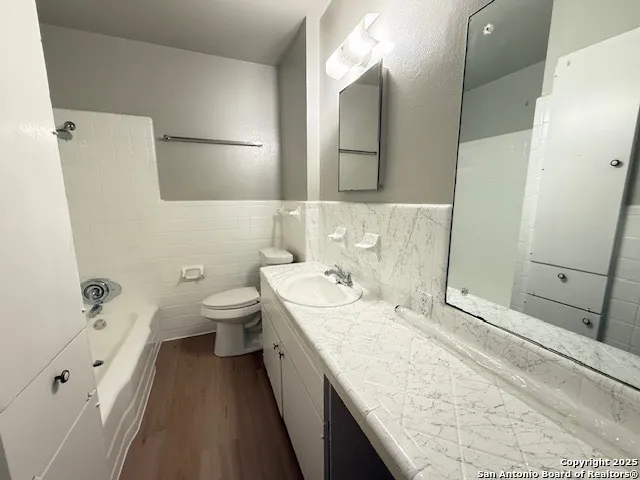 a bathroom with a granite countertop sink a large mirror and a toilet