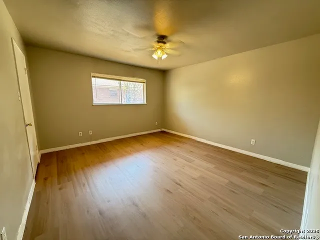 a view of a room with wooden floor and a ceiling fan
