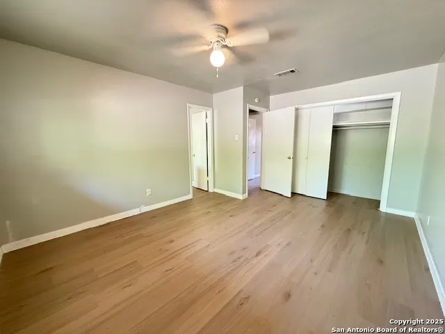 an empty room with wooden floor and a ceiling fan