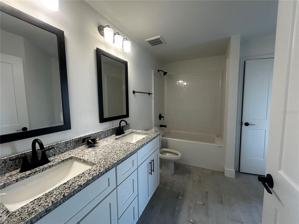 498 Santiguay Street Punta Gorda, FL 33983 - Photo 12 of 28 a bathroom with a granite countertop sink double mirror and a bathtub