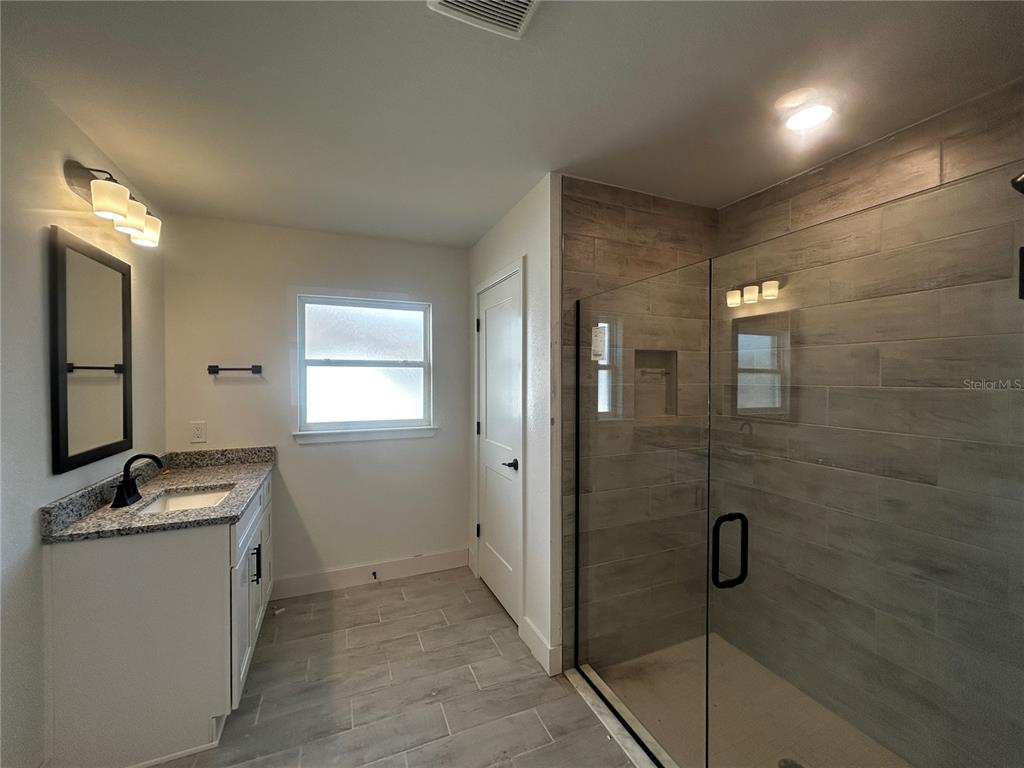 498 Santiguay Street Punta Gorda, FL 33983 - Photo 9 of 28 a bathroom with a granite countertop sink a mirror and shower