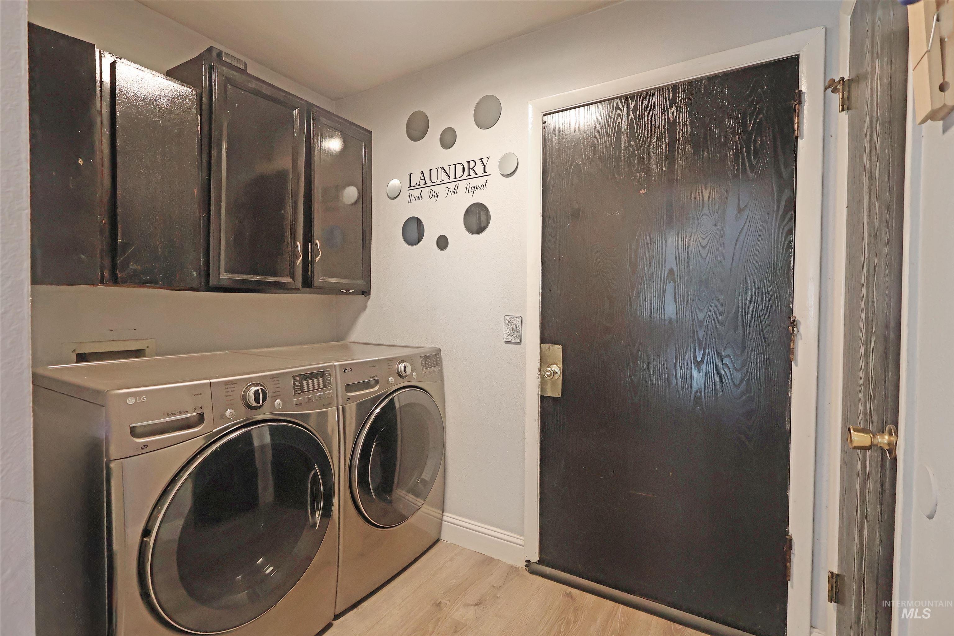 412 Linden Street Rupert, ID 83350 - Photo 8 of 17 Laundry room with light wood-style flooring, washing machine and clothes dryer, and cabinet space