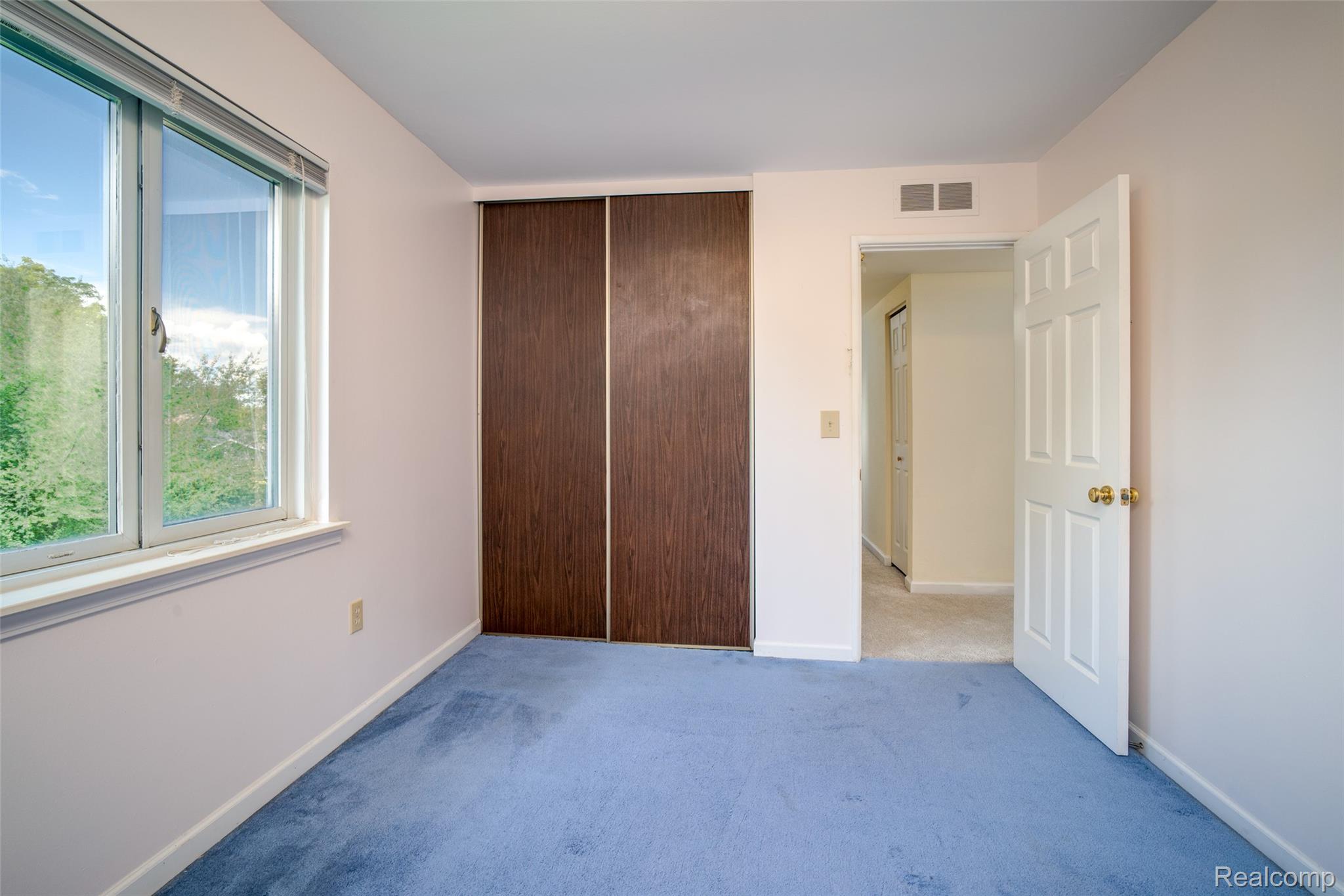 22533 Winfield Road Novi, MI 48375 - Photo 18 of 43 Spacious room featuring a large window, wood-finish closet doors, light blue carpeting, white trim, and a white six-panel door