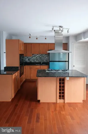 a kitchen with stainless steel appliances kitchen island wooden floors and cabinets