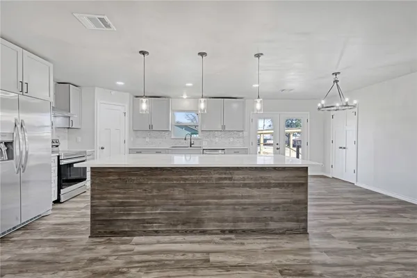 a large white kitchen with kitchen island a sink stainless steel appliances and cabinets
