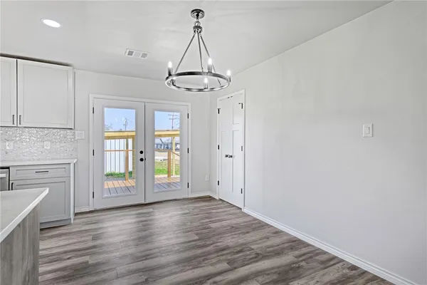 a view of an empty room with window and wooden floor
