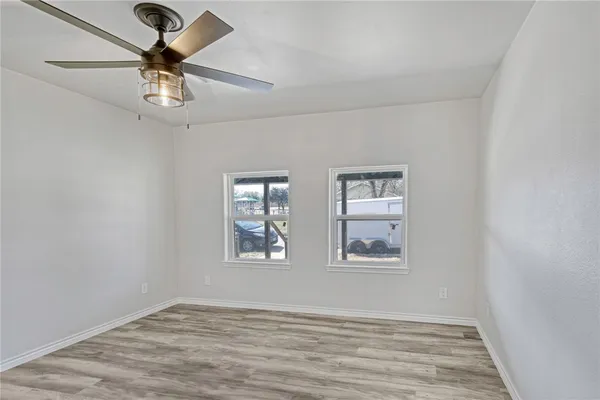 a view of empty room with wooden floor and fan