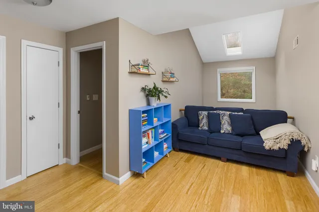 a living room with a couch and a bookshelf with wooden floor