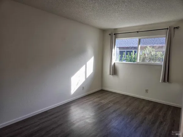 a view of an empty room with wooden floor and closet
