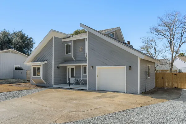 a front view of house with yard and trees in the background