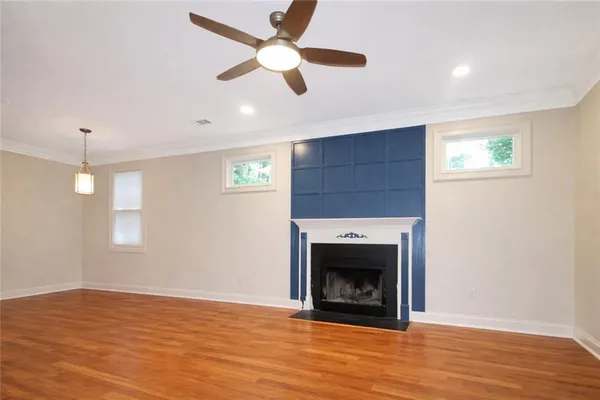 a view of empty room with wooden floor fan and window