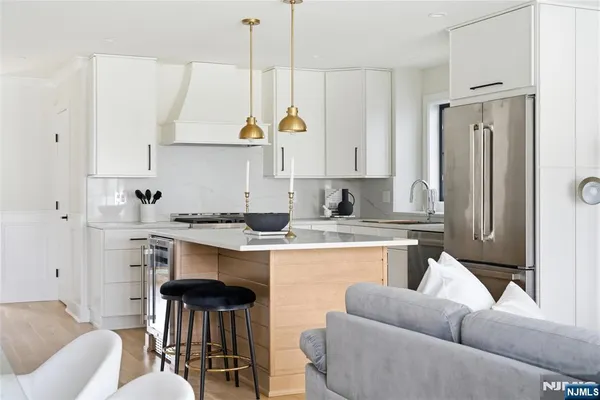 a kitchen with stainless steel appliances granite countertop a refrigerator a stove and white cabinets with wooden floor