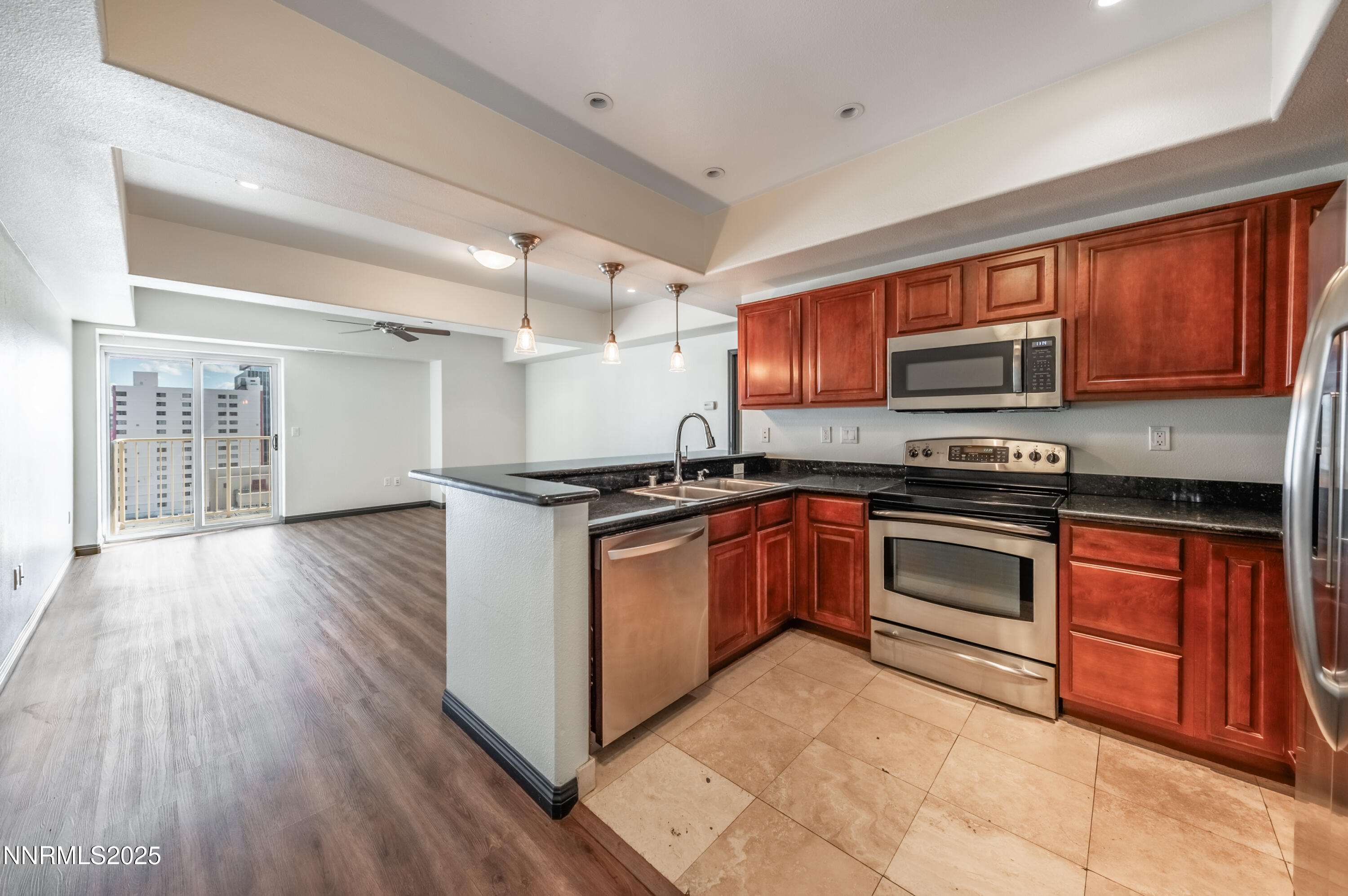 a kitchen with granite countertop wooden floors stainless steel appliances and a window