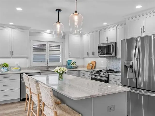a kitchen with kitchen island a counter space stainless steel appliances and cabinets