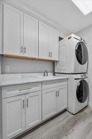 a utility room with white cabinets and sink