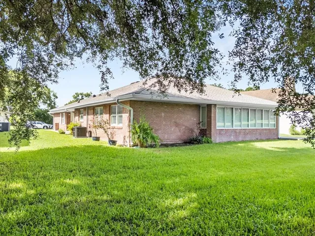 a view of a house with a yard and large trees