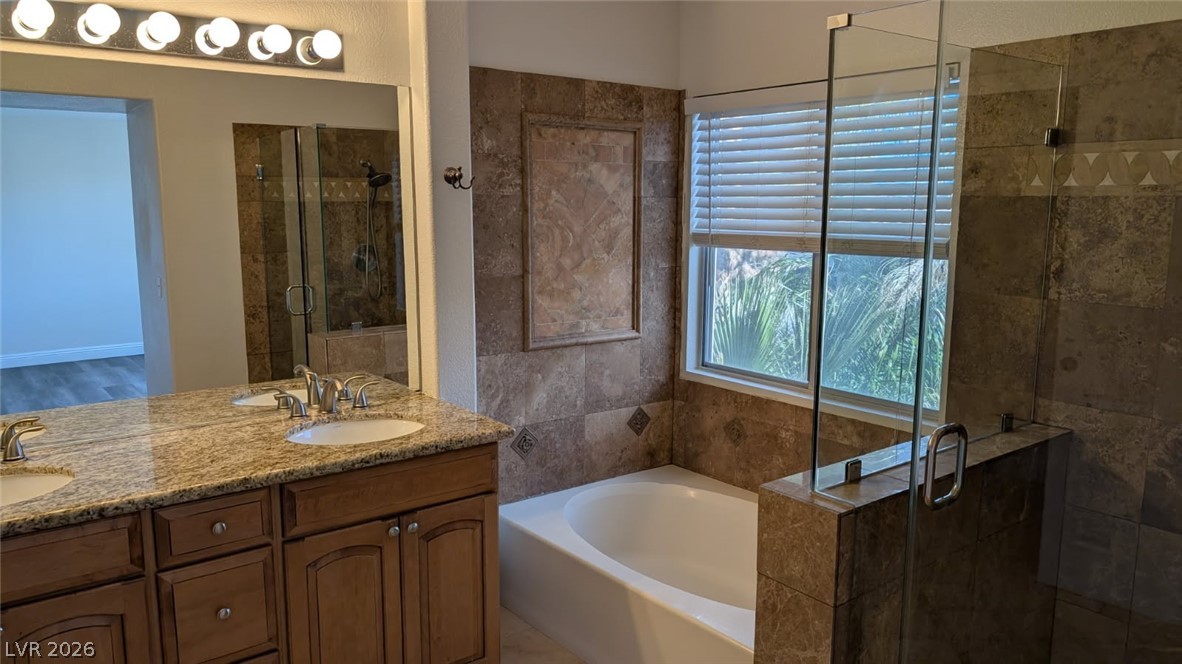 2670 Ridgewater Circle Henderson, NV 89074 - Photo 14 of 22 This bathroom features a large vanity, a spacious bathtub, and a separate shower.