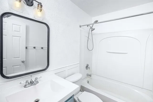 a bathroom with a granite countertop sink a toilet and shower