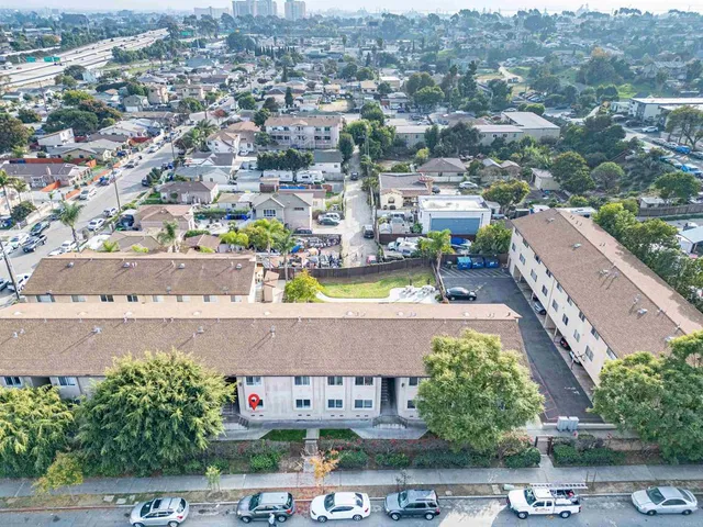 an aerial view of a city with lots of residential buildings ocean and mountain view in back
