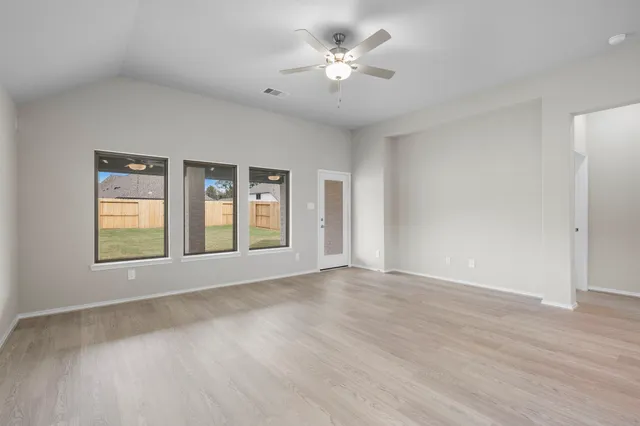 a view of an empty room with a window and wooden floor