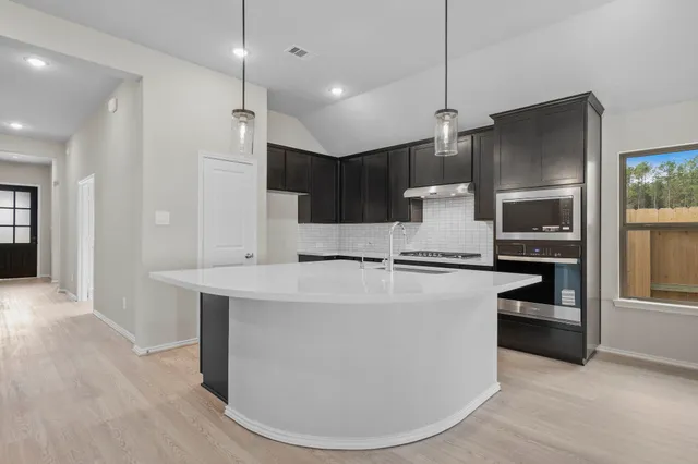 a large kitchen with stainless steel appliances kitchen island granite countertop a refrigerator and a stove top oven