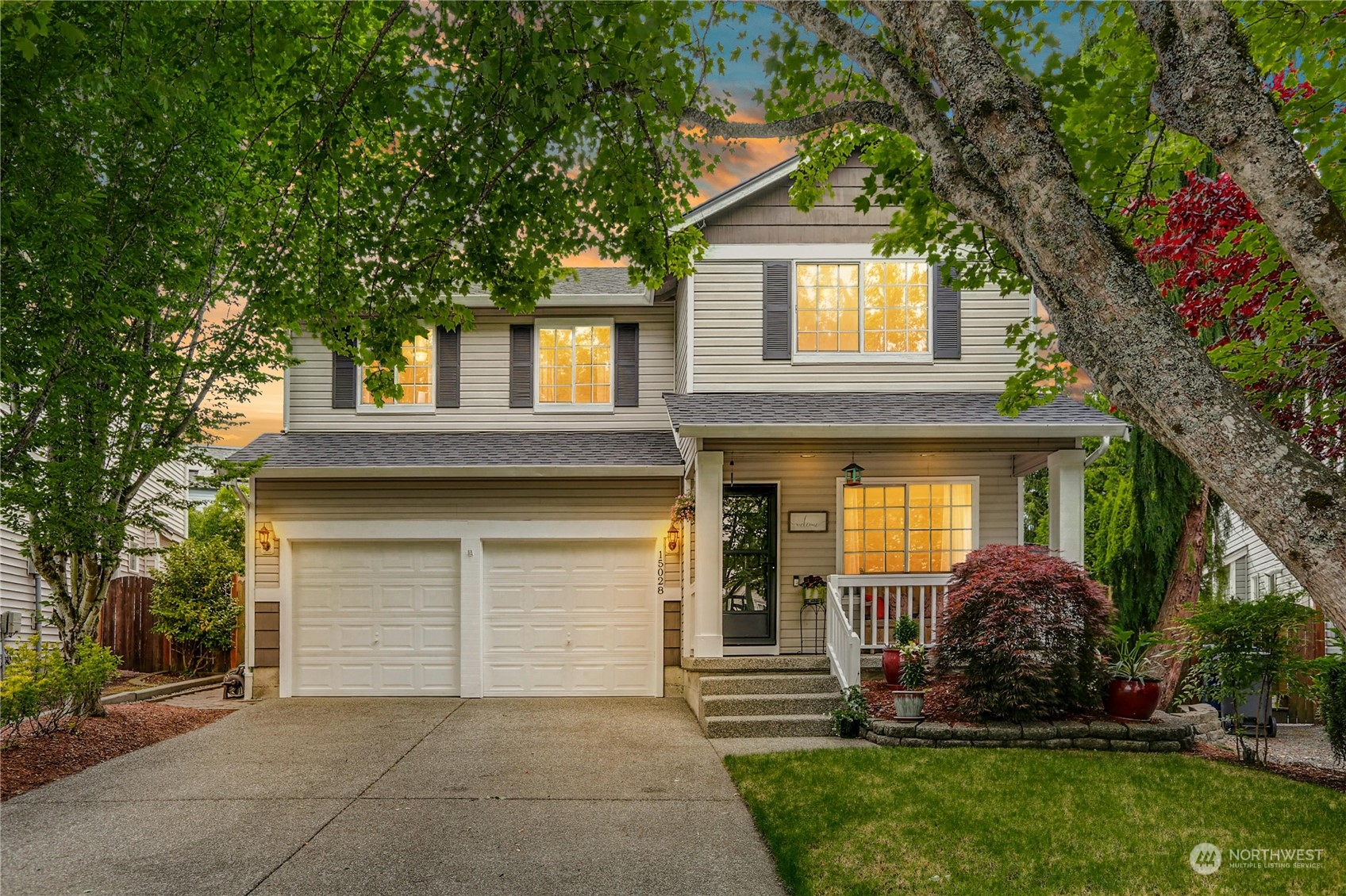 a front view of a house with a garden and trees