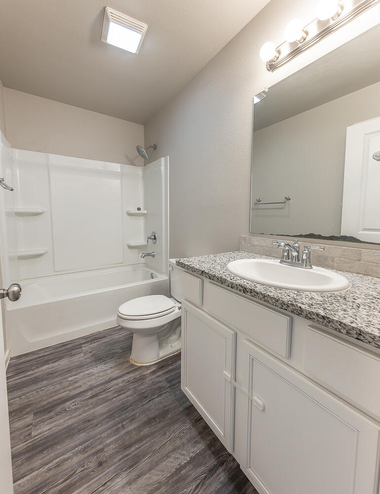 7526 31st Place Lubbock, TX 79407 - Photo 15 of 22 a bathroom with a granite countertop toilet a sink and a mirror