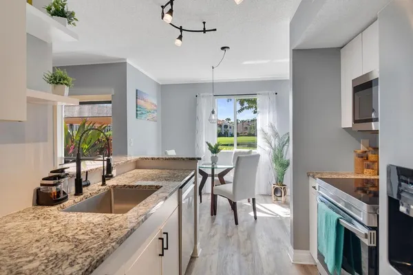 a kitchen with granite countertop a sink a counter top space and stainless steel appliances