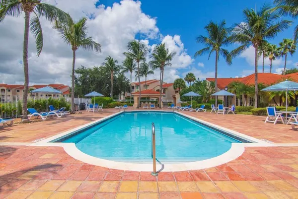 a swimming pool with outdoor seating yard and palm trees