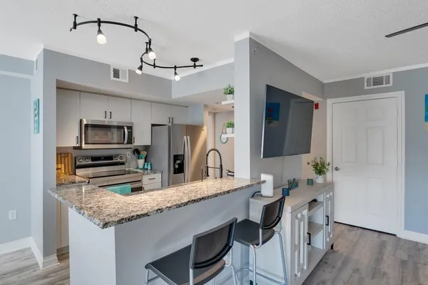 a kitchen with granite countertop a stove a sink and a refrigerator