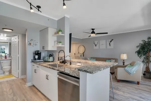 a kitchen with stainless steel appliances granite countertop a sink dishwasher and cabinets with wooden floor