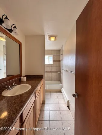 a bathroom with a granite countertop sink a mirror and shower