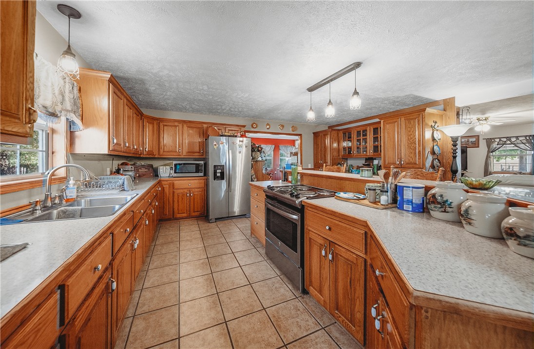 21587 West Hickory Flat Road Springdale, AR 72764 - Photo 19 of 45 Spacious kitchen with abundant wood cabinetry, center island, extensive counter space, tile flooring, and stainless-steel appliances.