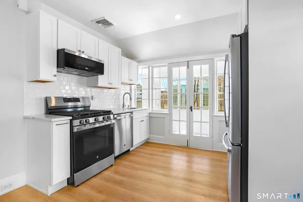 a kitchen with stainless steel appliances granite countertop a refrigerator and a stove top oven