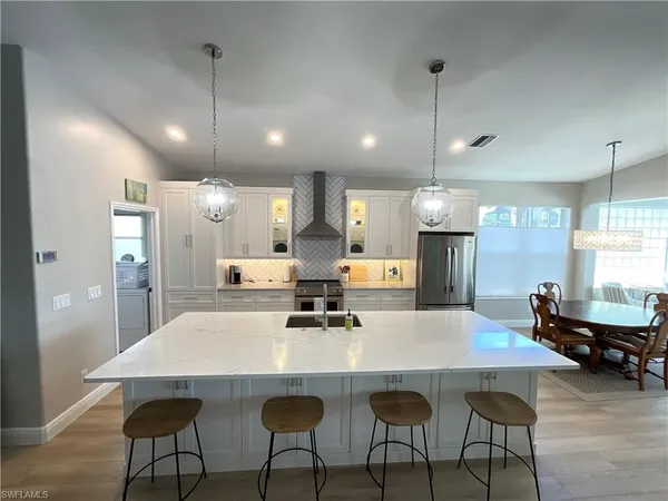 a kitchen with stainless steel appliances kitchen island a table chairs and a refrigerator