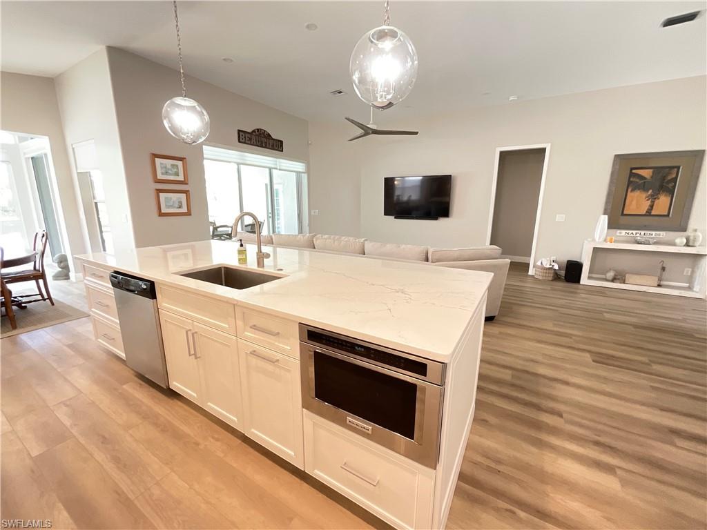 1709 Marsh Run Naples, FL 34109 - Photo 4 of 19 a large white kitchen with sink a microwave a stove and white countertops with wooden floor