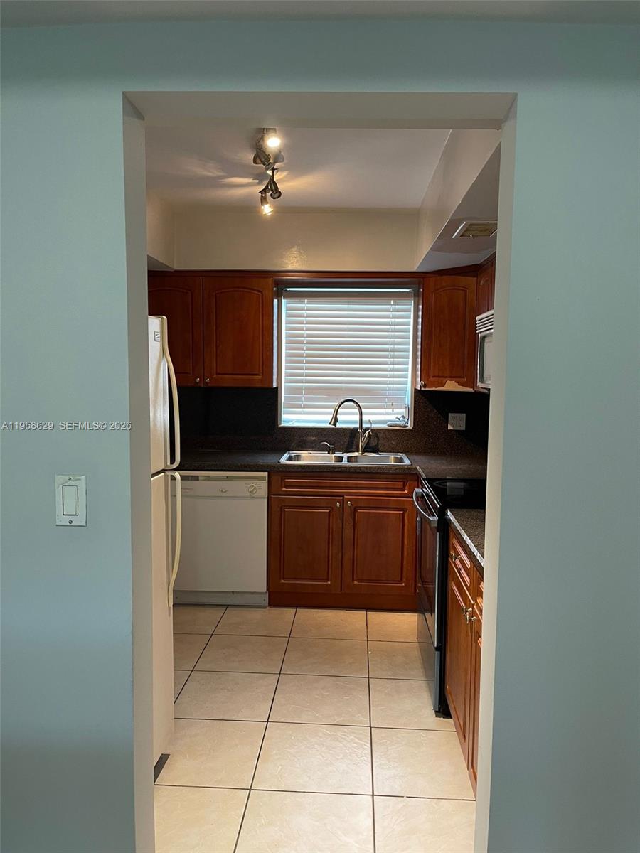 7670 Southwest 82nd Street, Unit H113 Miami, FL 33143 - Photo 3 of 14 a kitchen with a refrigerator and a stove top oven