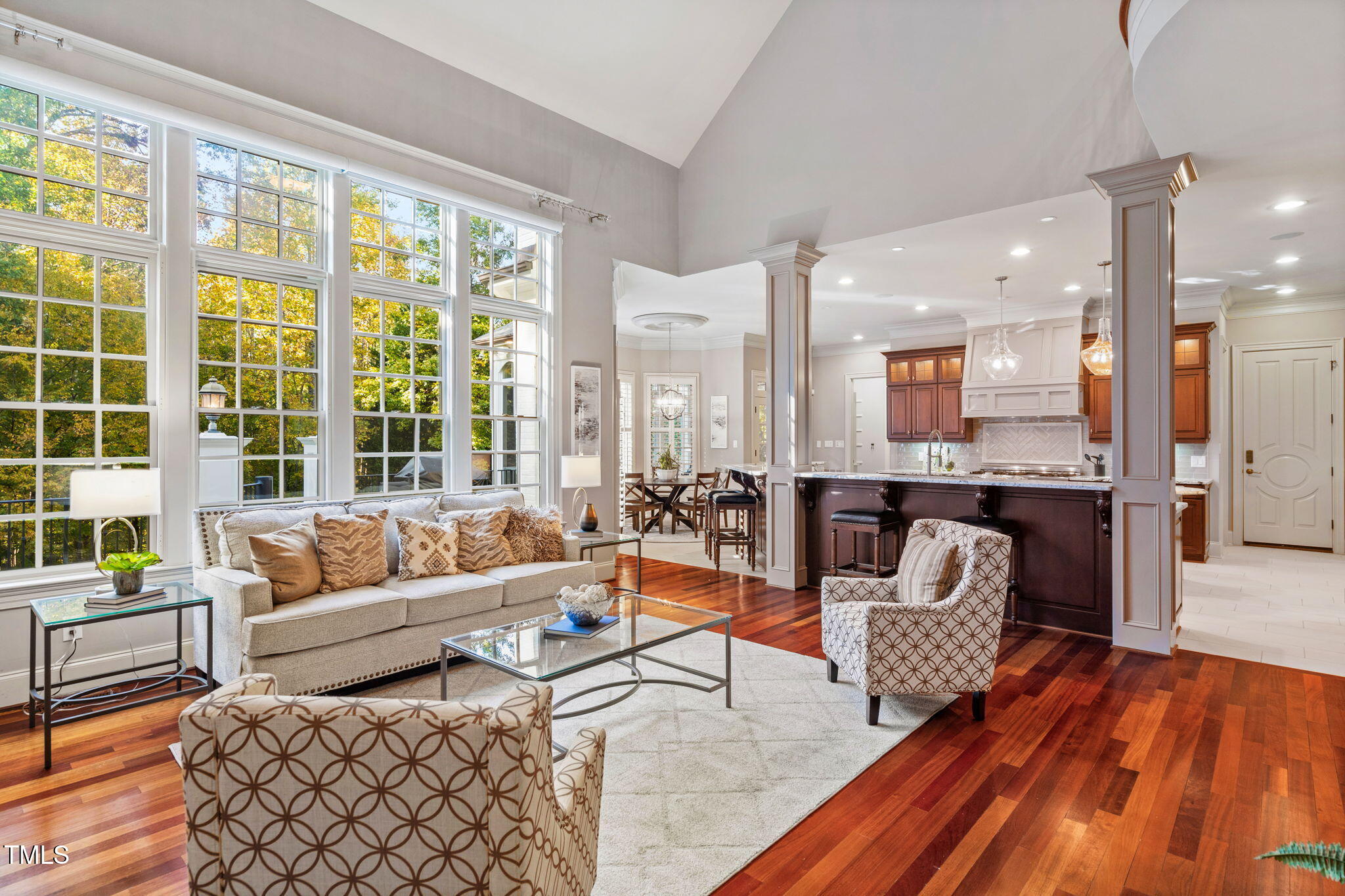 Open-concept living flows into a sun-drenched family room with stone fireplace and remote-controlled shades. French doors lead to a vaulted three-season EZE-Breeze room with its own stone fireplace—perfect for year-round entertaining.