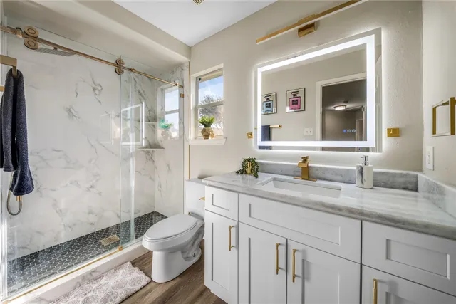 a bathroom with a granite countertop sink toilet and shower