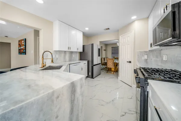 a kitchen with stainless steel appliances granite countertop a stove a sink and a microwave