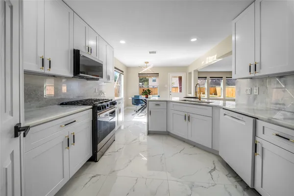 a kitchen with stainless steel appliances granite countertop a sink and dishwasher a refrigerator with white cabinets