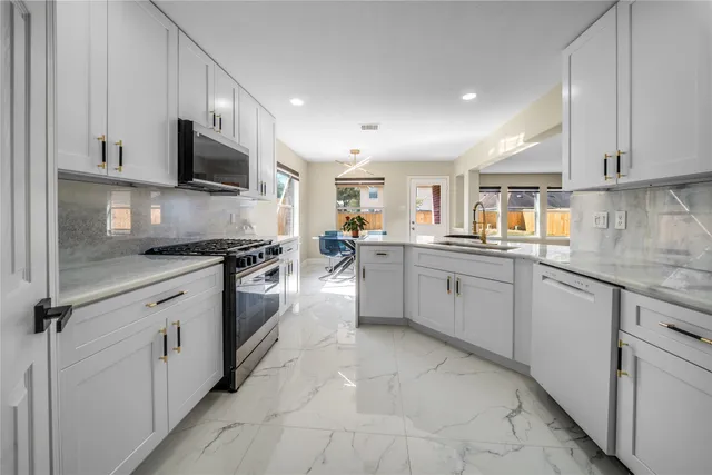 a kitchen with stainless steel appliances granite countertop a sink and dishwasher a refrigerator with white cabinets