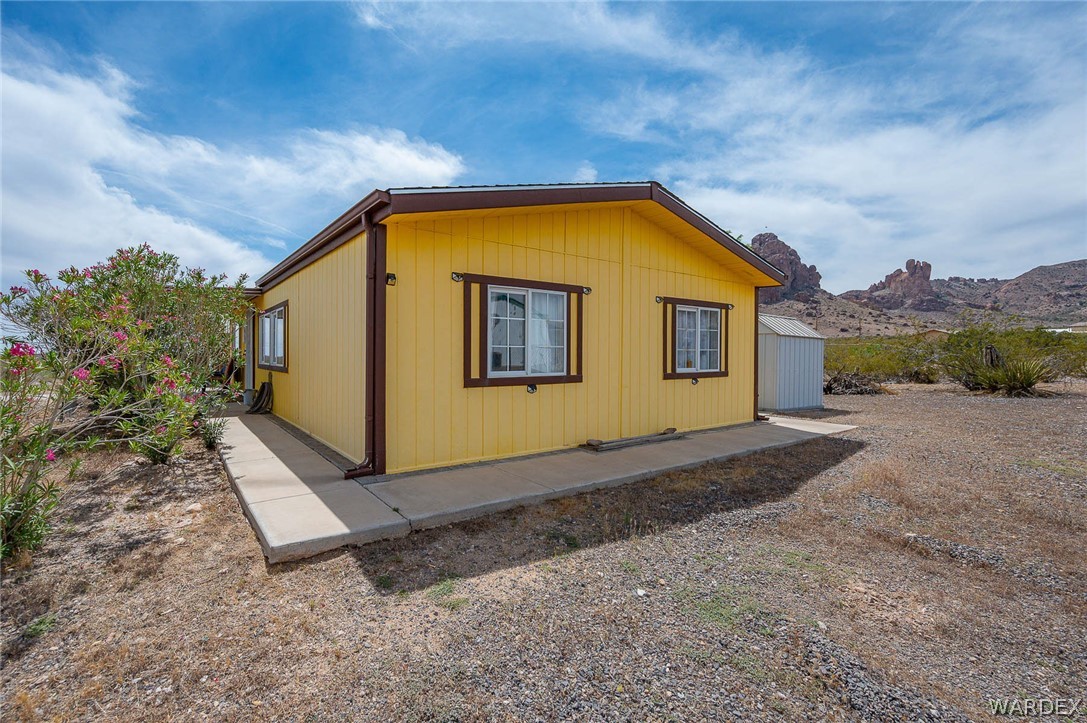 2465 Egar Road Golden Valley, AZ 86413 - Photo 10 of 98 The property features a yellow exterior with brown trim and a paved walkway along the side