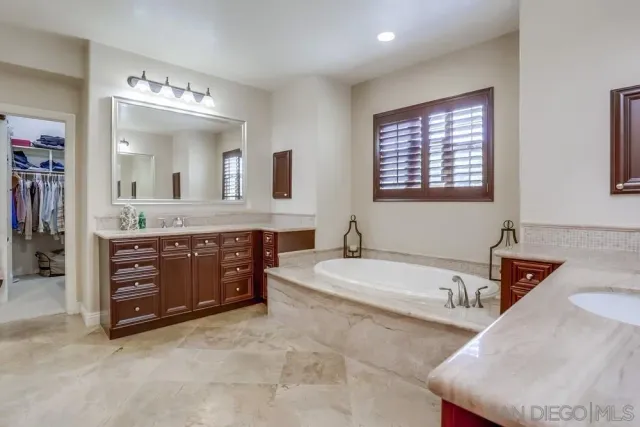 a spacious bathroom with a granite countertop sink mirror and bathtub