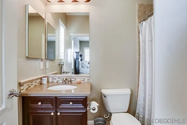 a bathroom with a granite countertop toilet a sink and a mirror